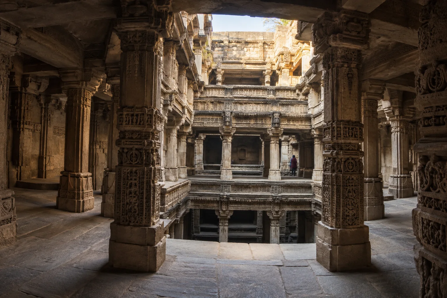 Резные колонны и затенённые ярусы ступенчатого колодца Adalaj рядом с Ахмадабадом